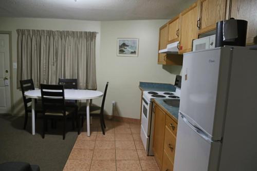a kitchen with a table and a white refrigerator at SlumberLodge Hotel in Penticton