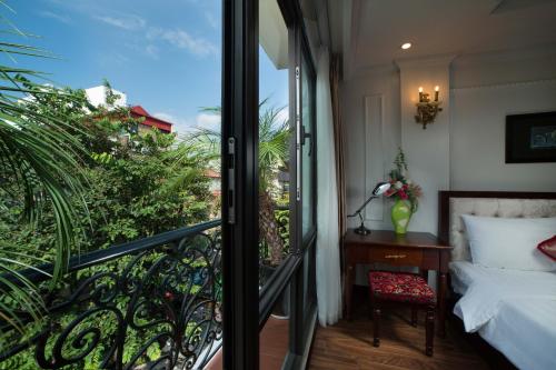 a bedroom with a balcony with a bed and a desk at Golden Sail Hotel & Spa in Hanoi