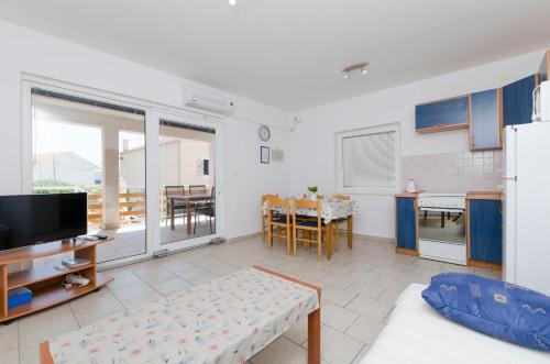 ein Wohnzimmer mit einem Sofa und einem TV sowie eine Küche in der Unterkunft Apartments Marija Jug in Primošten