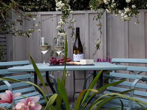 a blue table with wine glasses and wine bottles at Mapua Studio Quality Accommodation in Mapua