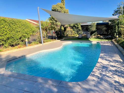 a swimming pool with a white umbrella over it at Best Western Plus All Settlers Motor Inn in Tamworth