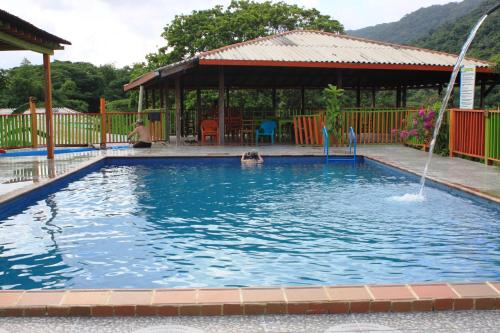 a pool with a gazebo and two people in the water at Cabañas Ecoturisticas Y Club Gaira Tayrona in Santa Marta