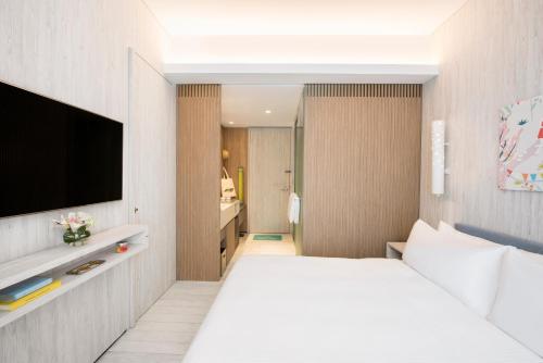 a bedroom with a white bed and a television at Village Hotel Sentosa by Far East Hospitality in Singapore