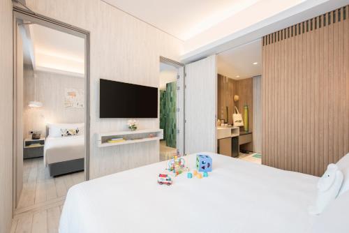 a bedroom with a white bed and a large mirror at Village Hotel Sentosa by Far East Hospitality in Singapore