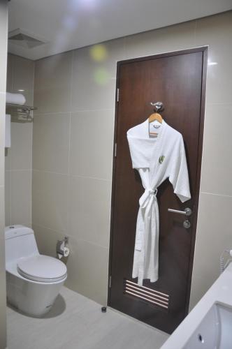 a bathroom with a toilet and a robe on a door at Golden Tulip Pontianak in Pontianak