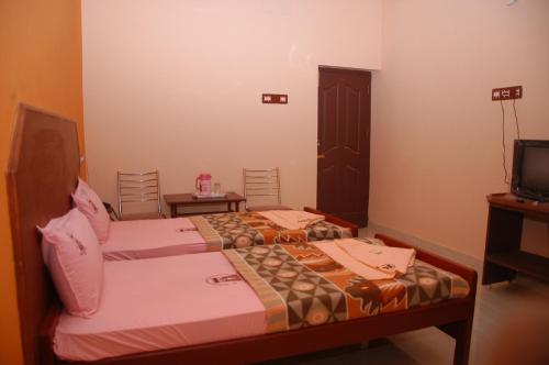1 Schlafzimmer mit 2 Betten und einem TV in der Unterkunft VENKKATRAMANAA RESIDENCY in Kumbakonam