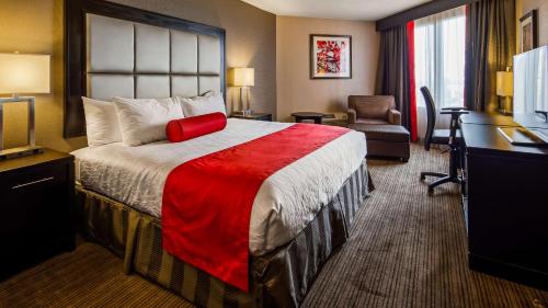 a hotel room with a large bed and a desk at Best Western Plus Waterfront Hotel in Windsor