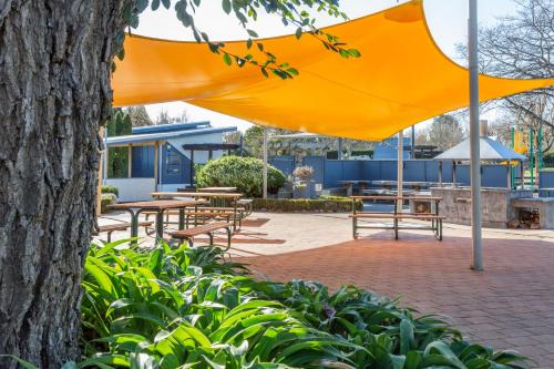 an orange umbrella over benches and tables in a park at Hastings TOP 10 Holiday Park in Hastings
