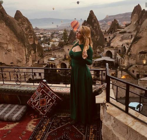 a woman in a green dress standing on a ledge at Elite Cave Suites in Goreme
