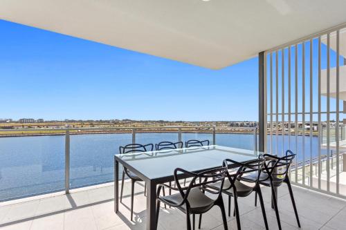 a table and chairs on a balcony with a view of the water at North Shore Oceanside Kawana in Kawana Waters