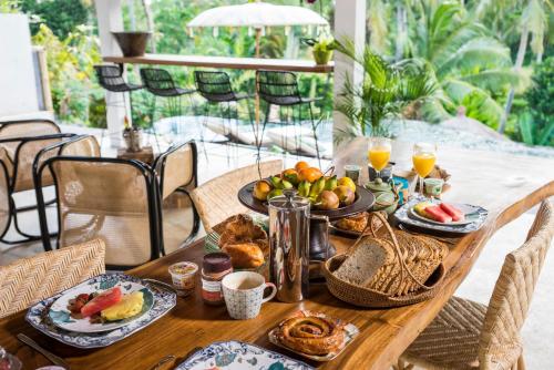 a wooden table with breakfast foods and drinks on it at Calma Ubud Suite & Villas - Rice Fields View, Infinity Pool ! in Ubud