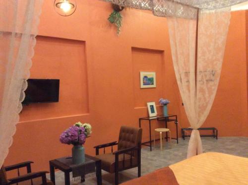 a bedroom with orange walls and a bed and chairs at Pupiang po Da Arte Resort in Dan Sai