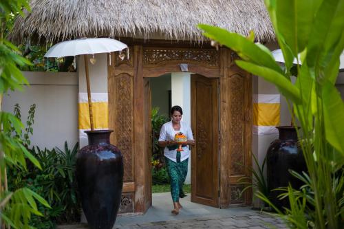 a woman standing in a doorway with a plate of food at Calma Ubud Suite & Villas in Ubud