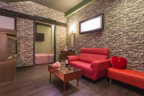 a living room with a red couch and a brick wall at Giyoche Motel in Wanli