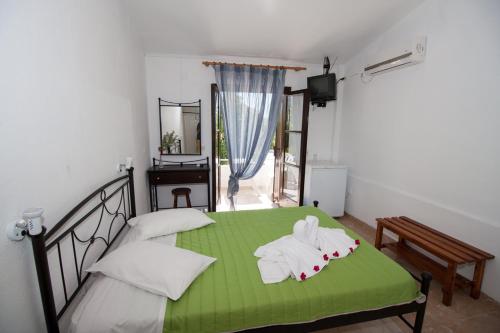 een slaapkamer met een groen bed en handdoeken bij Kefalonia Beach Hotel & Bungalows in Lixouri
