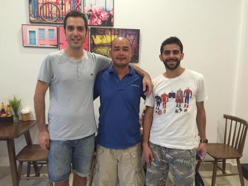 three men standing next to each other in a room at candyinn in Hue