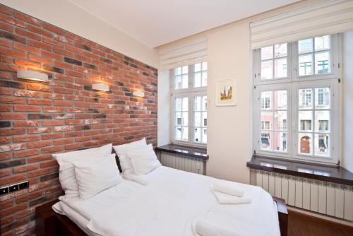 グダニスクにあるGdańsk Holidayのレンガの壁と白いベッドが備わるベッドルーム1室が備わります。