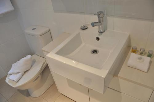 a white bathroom with a sink and a toilet at Annam Serviced Apartments in Sydney