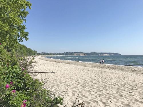 a beach with people walking on the sand and the water at Reetperle Lobbe - Ferienhaus mit Sauna (F 650) in Lobbe