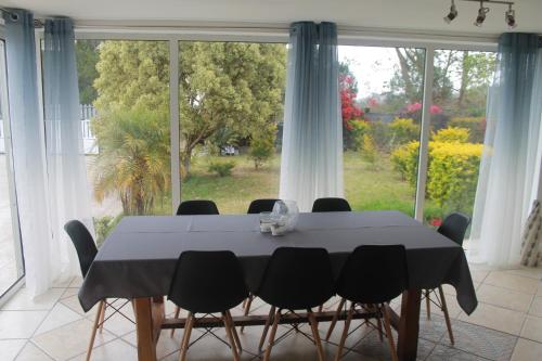 a dining room table with black chairs and a large window at Le Bougainvillier in La Plaine des Cafres