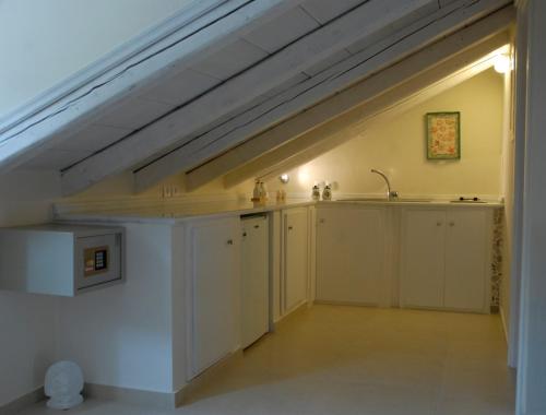 uma cozinha no sótão com armários brancos e um lavatório em Mistral Hotel em Hydra