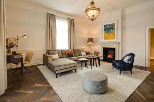 a living room with a couch and a fireplace at Steigenberger Icon Parkhotel Düsseldorf in Düsseldorf