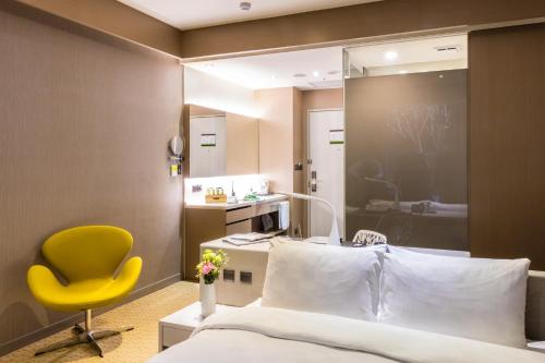 a hotel room with a bed and a yellow chair at Taipei 101 SPARKLE Hotel in Taipei
