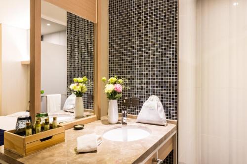 a bathroom with a sink and a mirror and flowers at Taipei 101 SPARKLE Hotel in Taipei