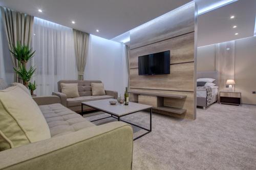 uma sala de estar com um sofá e uma televisão em Hotel Zlatna Žita em Pale