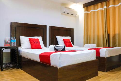 two beds in a hotel room with red pillows at RedDoorz @ Junquera Extension Cebu in Cebu City