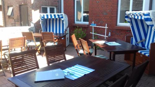 a patio with two tables and chairs with a laptop at Gasthaus Knudsen in Utersum
