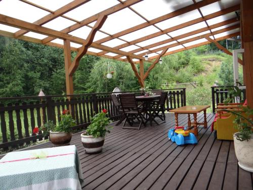 a wooden deck with a pergola and tables and chairs at Dom na wzgórzu in Gorlice