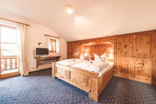 a bedroom with a large wooden bed and a desk at Hotel Garni Gästehaus Brand in Bad Wiessee