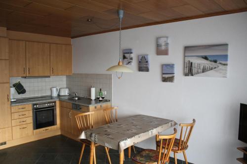 eine Küche mit einem Tisch und Stühlen sowie einem Tisch und einem Tisch und einer Küche in der Unterkunft Wangeroogeweg 3a in Wangerland