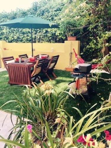 a table and chairs with an umbrella in a garden at BS VILLAS RC PORTO in Porto