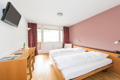 a hotel room with two beds and a desk at Hotel Sporting in Marbach