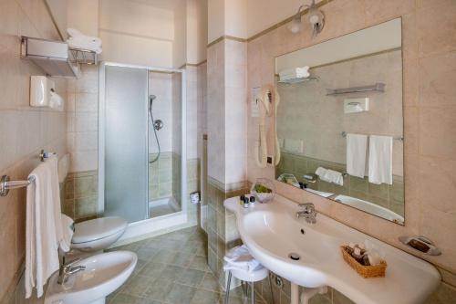 uma casa de banho com um lavatório, um WC e um espelho. em Hotel Metropol em Diano Marina