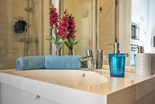 a bathroom sink with a blue glass and flowers on it at Blue Barqueta Studio in Faro