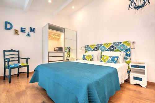 um quarto com uma cama com um cobertor azul e uma cadeira em Blue Barqueta Studio em Faro