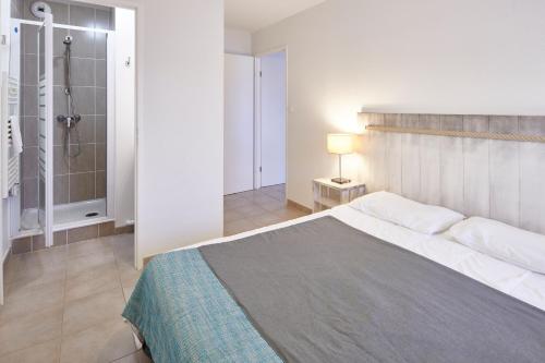 a bedroom with a large bed and a shower at Résidence Vacances Bleues Les Jardins d'Arvor in Bénodet