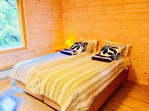 a bed in a wooden room with pillows on it at Villa by the Lake in Joutseno