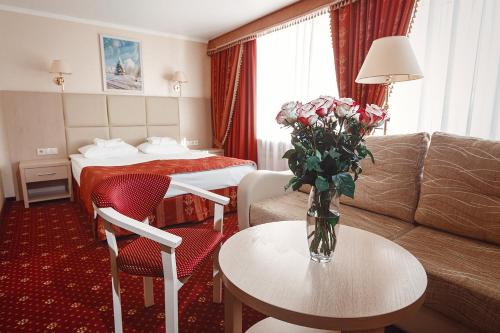 ノヴィ・ウレンゴイにあるAMAKS Polar Starのソファと花のテーブルが備わるホテルルームです。