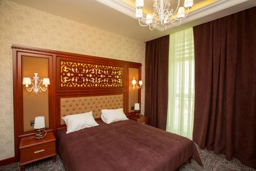 Un dormitorio con una cama grande y una lámpara de araña. en AZPETROL HOTEL QUSAR, en Qusar