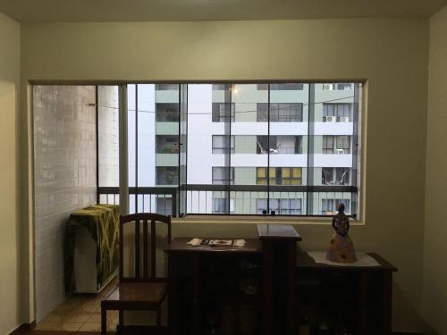 Ein Zimmer mit einem großen Fenster mit einem Schreibtisch und einem Tisch von sidx sidx sidx. in der Unterkunft Apartamento 3 quartos em frente ao Mar in Recife