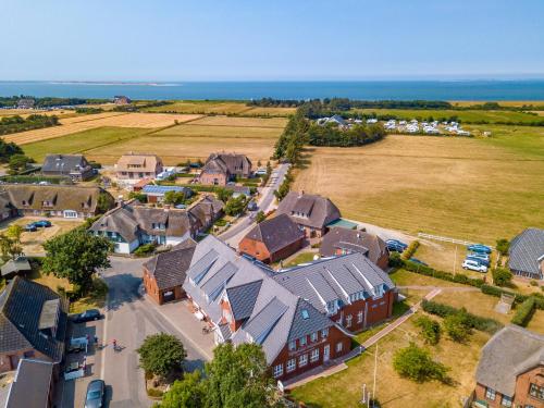 ein Luftblick auf ein Dorf mit Häusern und das Meer in der Unterkunft Gasthaus Knudsen in Utersum