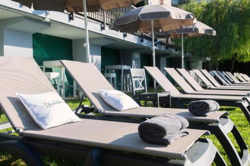 a row of lounge chairs and umbrellas at a resort at Hotel Bettina in Mergozzo