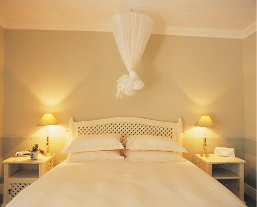 a bedroom with a white bed with two tables at High Hopes in Greyton