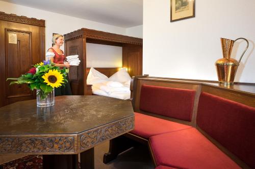 a woman standing in a hotel room with a table and flowers at Hotel der Löwen in Staufen in Staufen im Breisgau