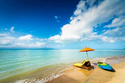 a boat and an umbrella on a beach at Chantaramas Beach Resort Koh Phangan in Baan Khai
