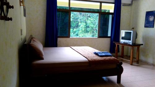a bedroom with a bed with a television and a window at JP hometel in Krabi